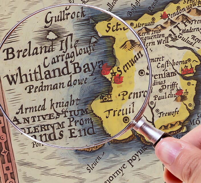 Hand hold a magnifying glass over West Cornwall Map